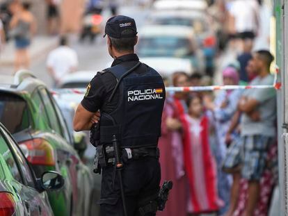 Un miembro de la Policía Nacional realiza un cordón policial frente a la vivienda de una joven asesinada en Almería, presuntamente a manos de su pareja.