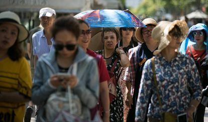 Un grupo de turistas se protegen del calor en Barcelona, el pasado junio.