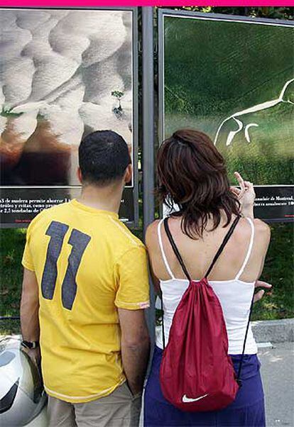Dos visitantes de la feria miran las fotografías de la exposición <i>La tierra vista desde el cielo</i>.