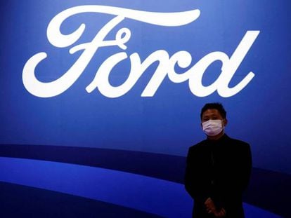 Un hombre posa frente al logo de la marca Ford en el salón del automóvil de Shanghái.