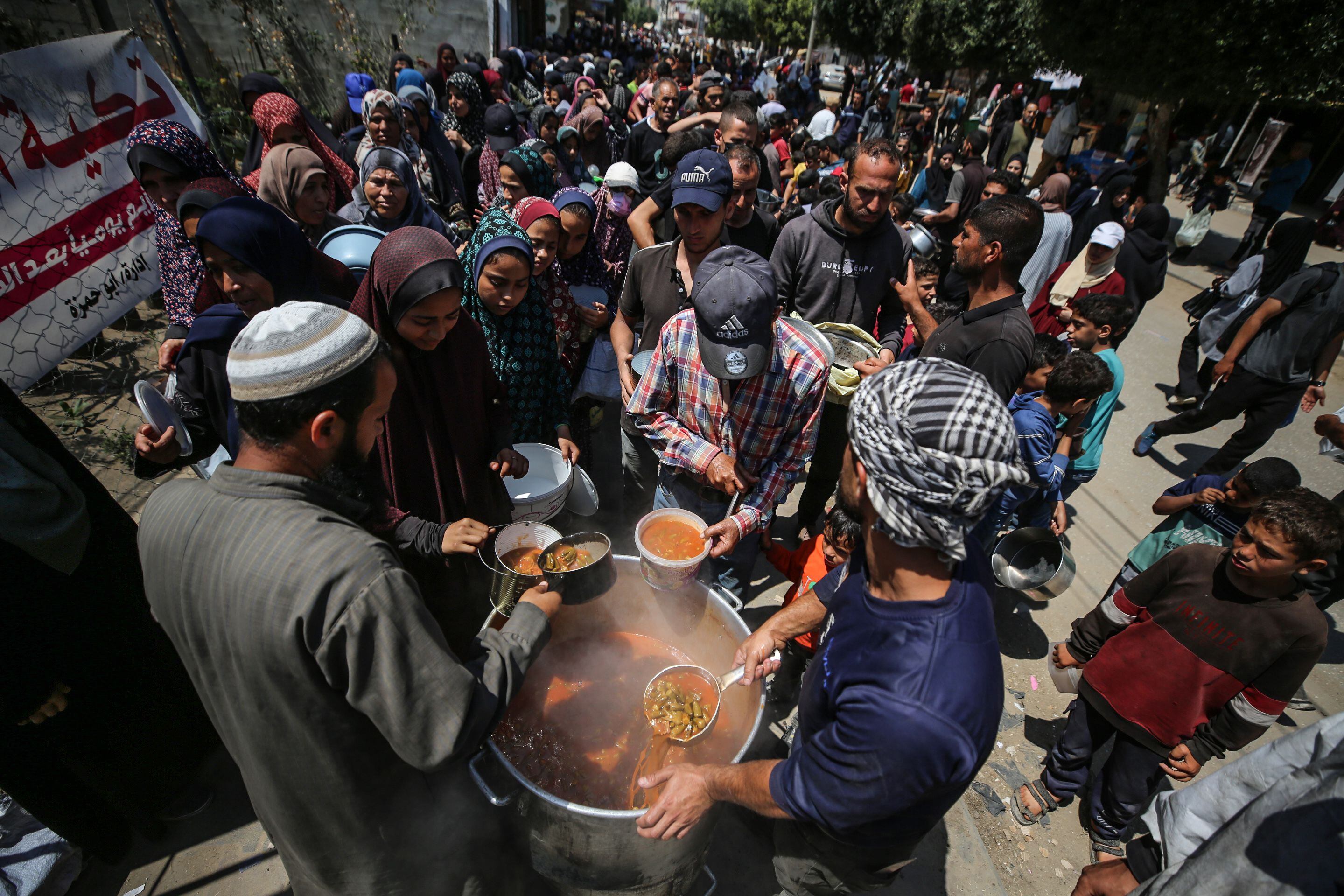 Palestinos desplazados reciben raciones de alimentos cocinados en un punto de donación en Deir al-Balah, en el centro de la Franja de Gaza, el 16 de abril de 2024.