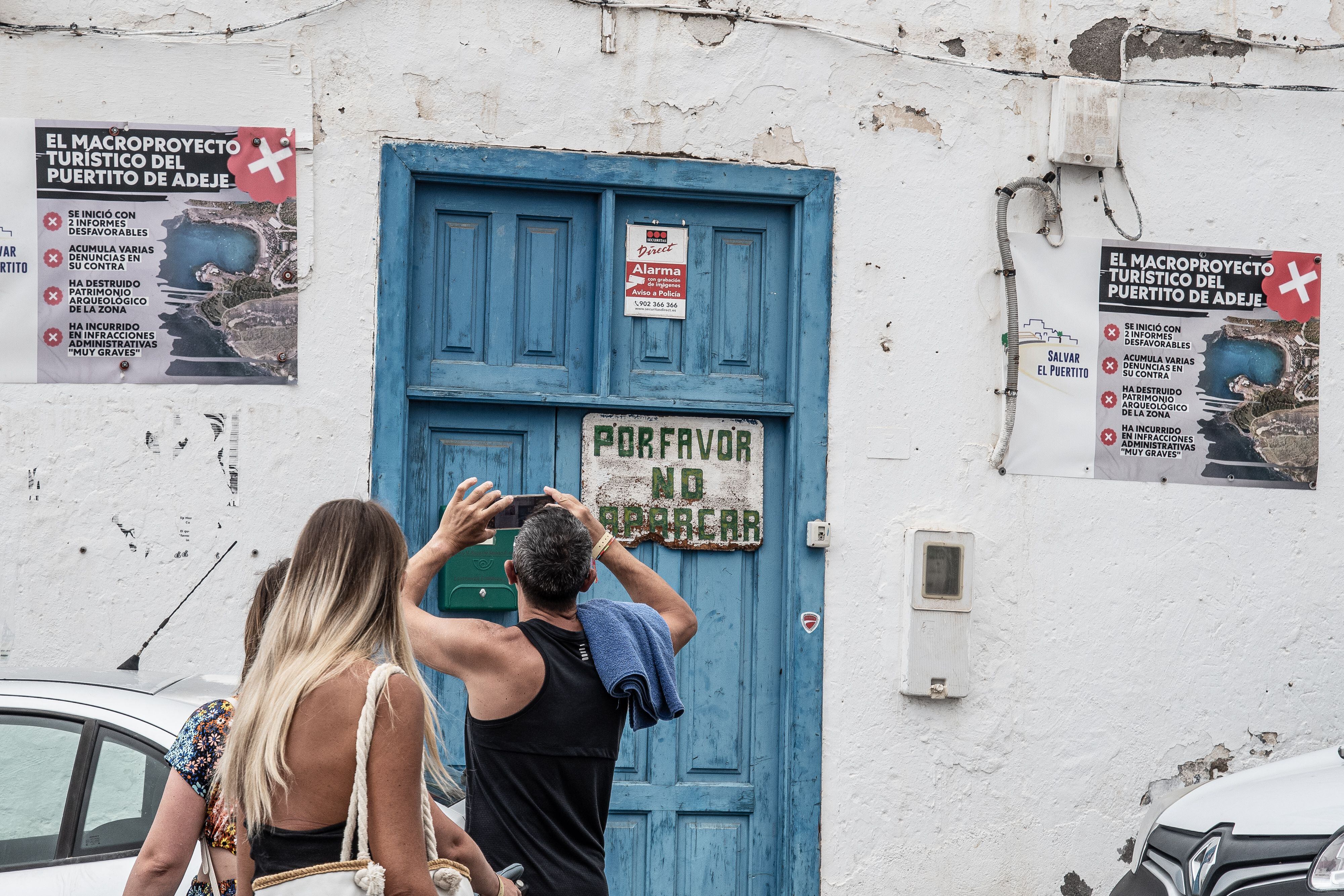 Turistas fotografían los carteles contra la urbanización del Puertito de Adeje, Tenerife. 