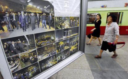 Dos personas caminan junto a varias imágenes de Kim Jong-un durante su llegada a Singapur, en el metro de Pyongyang (Corea del Norte).