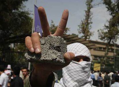Un estudiante iraní hace el signo de la victoria con una piedra en la mano durante la manifestación de solidaridad con el pueblo palestino.