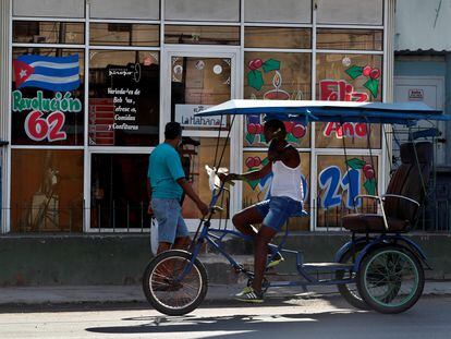 Dos personas pasan frente a una cafetería con imágenes en apoyo a la revolución cubana, en La Habana.