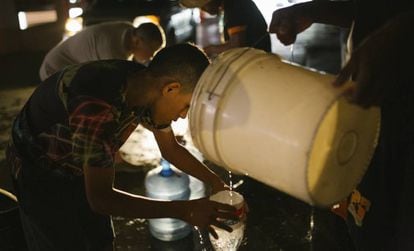 Un grupo de personas recoge agua durante el apagón en Caracas. 