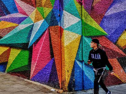 Un joven pasa junto a un grafiti en el barrio de Lavapiés.