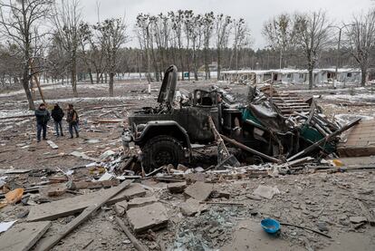 People stand next to a damaged vehicle in Brovary, near Kiev, on March 1.