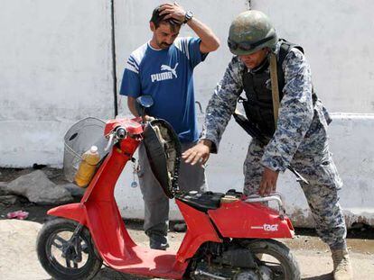 Un policía iraquí inspecciona una moto en un puesto de control en el barrio chií de Ciudad Sáder, en Bagdad.
