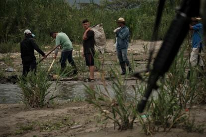 Personas trabajan en las trochas cerca al río Táchira mientras el ejército de Colombia patrulla la zona, el 29 de marzo.