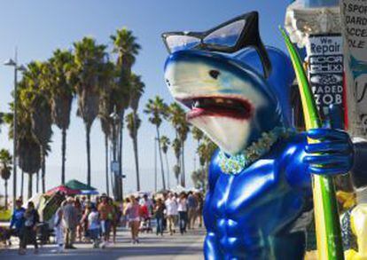 Un tiburón surfero entre el paisanaje de Venice Beach, en Los Ángeles (California).