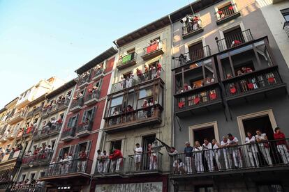 La calle Estafeta, inundada de humanos, fue el escenario de vistosas carreras, con la manada a velocidad de vértigo, cambios constantes en el liderazgo, caídas y atropellos diversos, y una marabunta multicolor cuando la comitiva llegó al tramo de Telefónica. En la foto, balcones repletos para seguir el tercer encierro de San Fermín, el primero de este año que se celebra en fin de semana. 