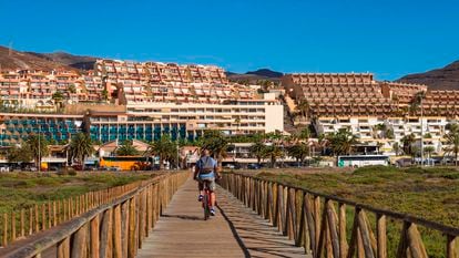 Un hombre monta en bici junto a varios edificios de apartamentos en Fuerteventura.