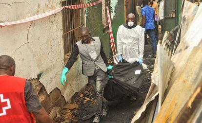 Dos personas transportan un cadáver tras el incendio en Monrovia, este miércoles en Monrovia.