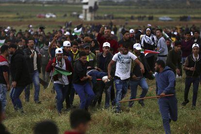 Manifestantes palestinos trasladan a un hombre herido por las tropas israelíes cerca de la frontera de la Franja de Gaza con Israel, el 30 de marzo.