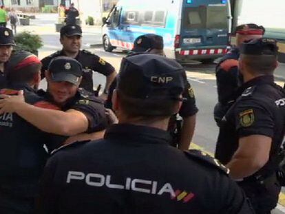 Un mosso se abraza a un policía nacional, rodeados de otros compañeros.