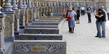 Varias personas observaban ayer los bancos de la Plaza de España de Sevilla tras su rehabilitación.