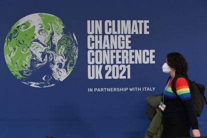 Una mujer pasa frente a un cartel que anuncia la cumbre del clima que se celebra en Glasgow.