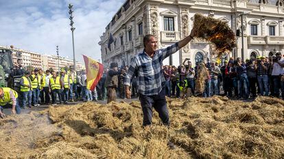 Un agricultor pega fuego este jueves a un montón de paja del arroz frente al edificio del Reloj, a la entrada del puerto de Valencia, durante la tractorada convocada por varias organizaciones agrarias.