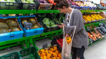 Una mujer compra verduras en un supermercado.