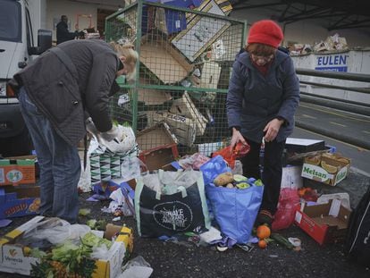 Dos personas recogen comida de la basura en Madrid, en diciembre de 2019.