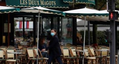 Una mujer pasa por delante del restaurante Les Deux Magots en Paris.