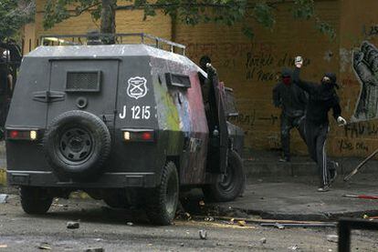 Un estudiante lanza piedras contra un vehículo de los carabineros chilenos en Santiago.