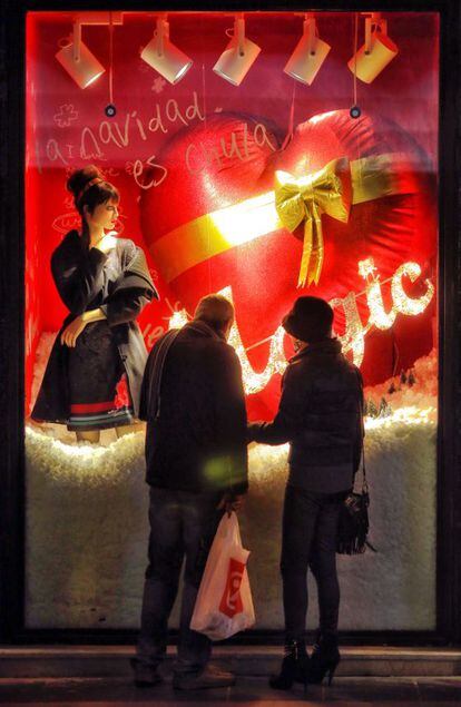 Una pareja observa un escaparate navide&ntilde;o del centro de Madrid.