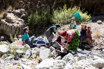 Un grupo de mujeres y niñas lavan en el río la ropa que han conseguido recuperar de entre los escombros.