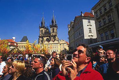 Los turistas se concentran en la plaza de la Ciudad Vieja de Praga, con la iglesia de Santa María de Thyn al fondo, para asistir al espectáculo de autómatas del reloj astronómico del Ayuntamiento.
