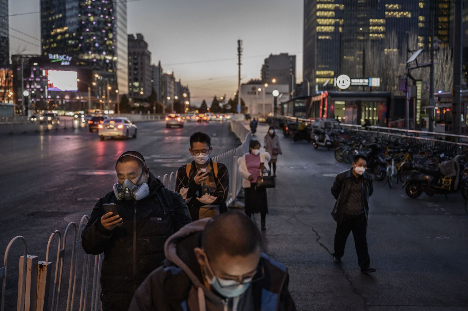 Plusieurs citoyens, tous portant des masques, font la queue pour attraper le bus le 20 mars à Pékin.