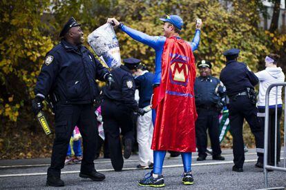 Un corredor disfrazado de 'Maratón Man' es cacheado por un agente de policía.