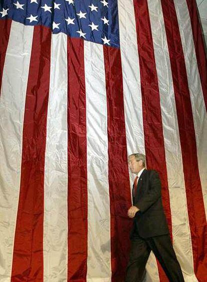 Bush pasa delante de una gran bandera de EE UU en Madison, Misisipi, en agosto de 2002.