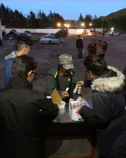 Voluntarios de "Bocata" reparten frascos de leche a un residente de la Cañada Real.