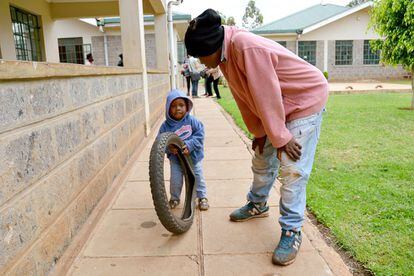 John enseña al hijo de una de las madres adolescentes a jugar con la rueda de una moto.