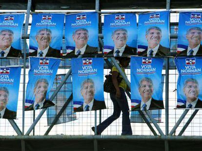 Una mujer cruza un puente con propagada del candidato de Arena 