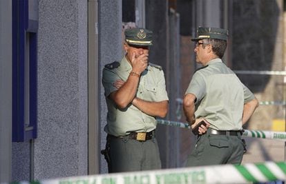 Dos guardias civiles conversan ante la sucursal bancaria de A Cañiza donde uno de sus compañeros ha fallecido esta mañana.