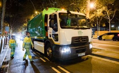 Dos trabajadores de recogida de residuos junto a uno de los nuevos camiones eléctricos adquiridos por el Ayuntamiento de Barcelona.