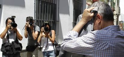 Domingo Enrique Castaño, sale de uno de los registros en sus casas oculto tras una chaqueta.