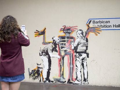 Una foven toma una foto de uno de los dos murales de Banksy.