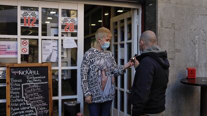 Una empleada de un bar de Sant Just Desvern (Barcelona) comprueba el certificado covid de un cliente en la entrada del local.