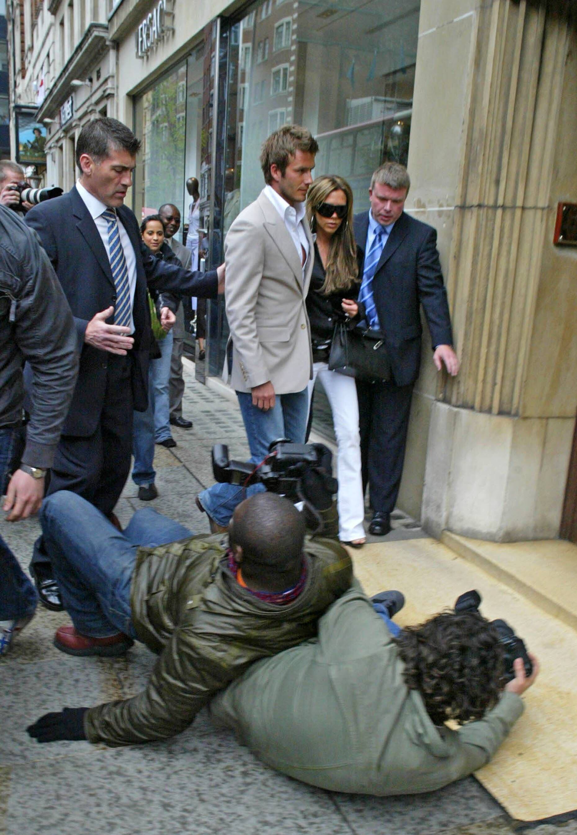 Dos paparazis caen al suelo tratando de fotografiar a David y Victoria Beckham, durante un día compras en Sloane Street, en Londres, en abril de 2006.