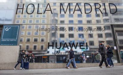 Varias personas pasean por la Gran Vía de Madrid, junto a la futura tienda de Huawei.