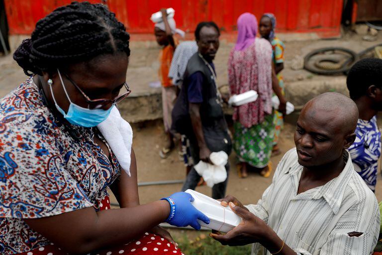 Una voluntaria distribuye comida a afectados por el confinamiento en Ghana.
