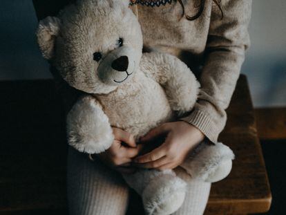 Una niña sostiene a su oso de peluche.