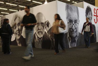 Asistentes a la Feria Internacional del Libro de Guadalajara pasean ante los retratos de escritores colocados en los pasillos.