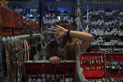 Una vendedora de relojes se tapa la cara en el Mercado de la Seda de Pekín