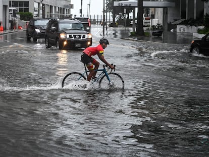 Un ciclista pasa por una calle inundada en Miami este lunes en medio de una intensa lluvia con viento por la tormenta Eta.