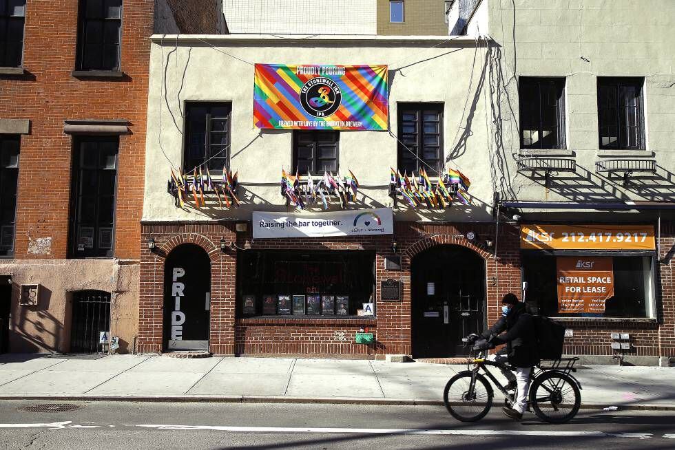 Un hombre con mascarilla y bicicleta pasa junto a la entrada de The Stonewall Inn (Nueva York), el bar que dio origen a las marchas del Orgullo.
