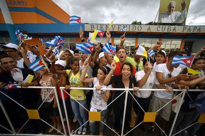 Fieles cubanos que esperaban la llegada del avi&oacute;n del Papa agitan sus banderas en el aeropuerto.